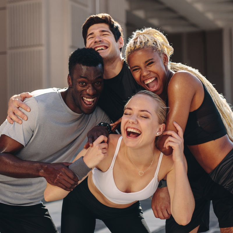 Four friends in athletic wear posing together outdoors