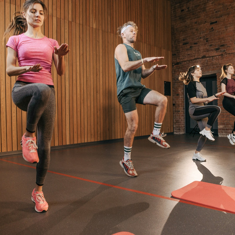 Group of people exercising in a studio with wooden walls and a brick wall.