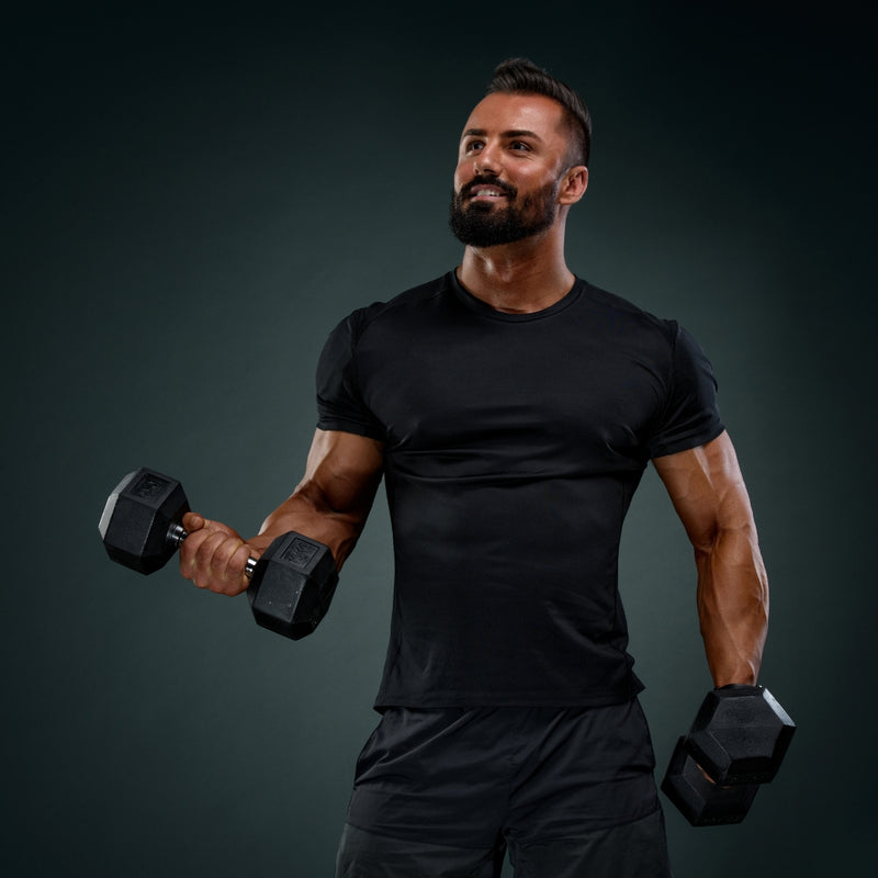 Man in black workout attire lifting dumbbells against a dark background